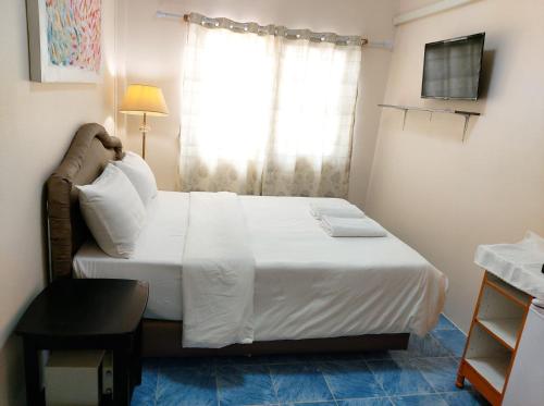 a bedroom with a white bed with a window at NB House in Karon Beach