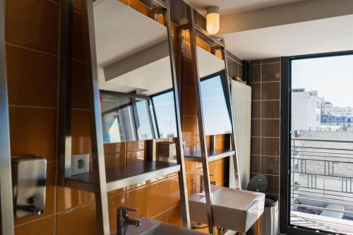 La salle de bains est pourvue de 2 lavabos et d'un miroir. dans l'établissement The People Paris Belleville, à Paris