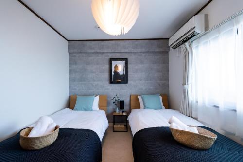 a bedroom with two beds and a window at Little Santa in Ginowan