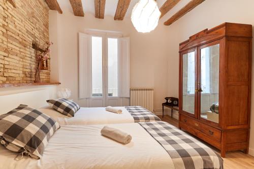 a bedroom with two beds and a wooden cabinet at El Roblón de la Estafeta in Pamplona