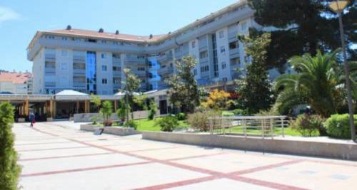 een groot wit gebouw met veel bomen en planten bij Laguna apartment in Tivat