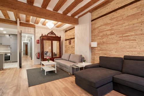 a living room with a couch and a brick wall at El Roblón de la Estafeta in Pamplona