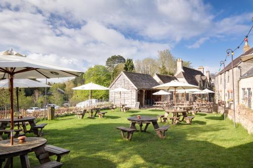 a group of picnic tables and umbrellas in a yard at The Royal Oak Tetbury in Tetbury