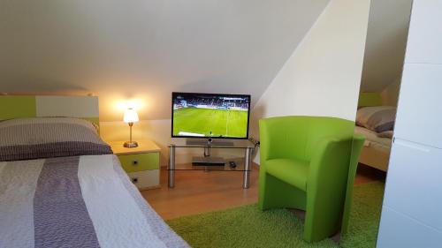 een slaapkamer met een groene stoel en een flatscreen-tv bij Meeresbrise Asternweg in Zinnowitz