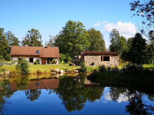 una casa junto a un lago con un edificio en Atpūtas Vieta Raudiņi, en Kaltene