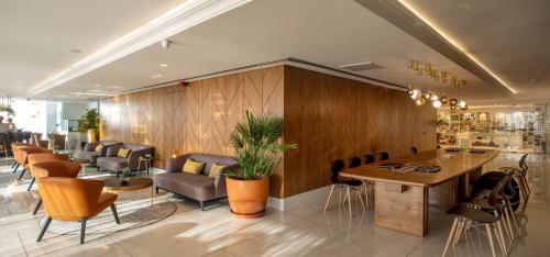 a lobby with chairs and tables in a restaurant at Carlton Tel Aviv Hotel – Luxury on the Beach in Tel Aviv