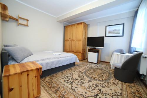 a small bedroom with a bed and a television at Rezydencja Legrams in Darłowo
