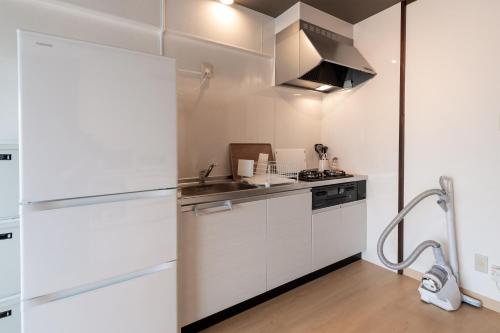 a white kitchen with a sink and a refrigerator at Little Santa in Ginowan