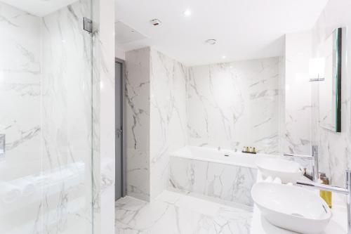 a white bathroom with a tub and a sink at The Scotsman Hotel in Edinburgh