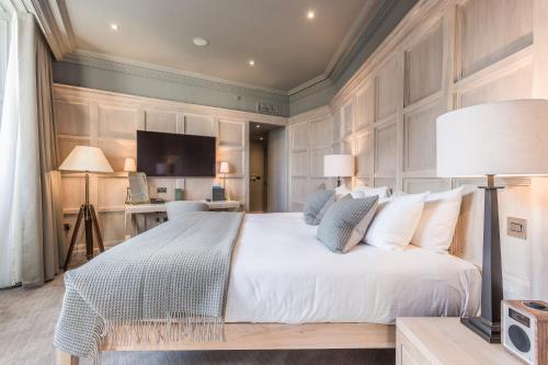 a bedroom with a large white bed and a television at The Scotsman Hotel in Edinburgh