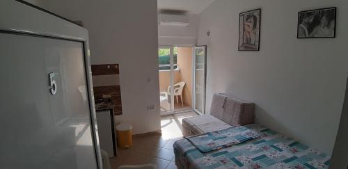 a small room with a bed and a sliding glass door at Apartmani "Ravić" in Sutomore