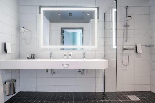 een witte badkamer met een wastafel en een spiegel bij Thon Hotel Cecil in Oslo