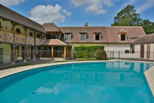 une piscine devant une maison avec un bâtiment dans l'établissement Domaine Du Roncemay - Hôtel, Restaurants, Spa & Golf, à Aillant-sur-Tholon