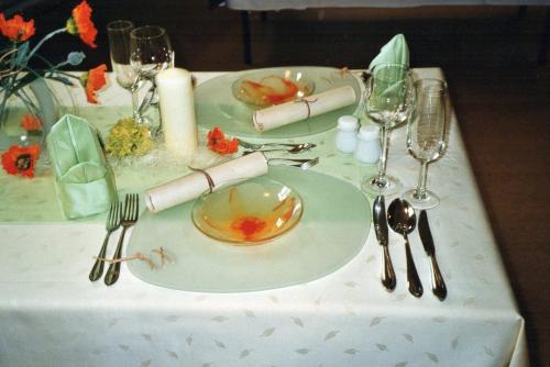 a table with a plate and wine glasses on it at Hotel Carola in Olbernhau