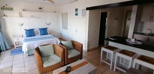 a bedroom with a bed with blue pillows and two chairs at Private Kaliva 605, Club Mykonos Resort in Langebaan