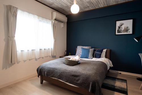 a bedroom with a blue accent wall and a bed at Little Santa in Ginowan