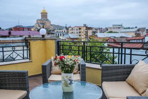 una mesa de cristal con un jarrón de flores en el balcón en Vincent en Tiflis