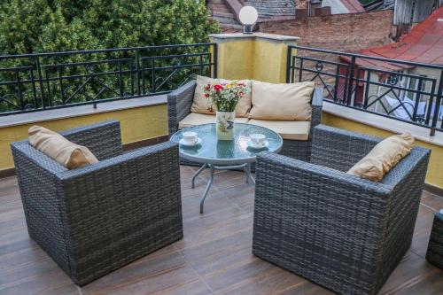 a patio with two wicker chairs and a table on a balcony at Vincent in Tbilisi City