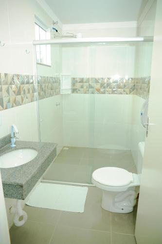 a white bathroom with a toilet and a sink at London Executive Hotel in Cafelândia