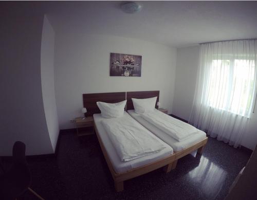 a bedroom with a bed with white sheets and a window at Gästezimmer Faut in Schorndorf