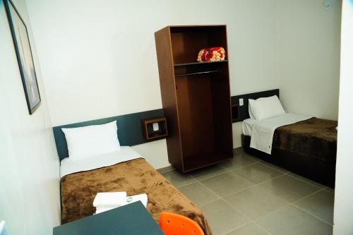 a room with two beds and a desk and a table at London Executive Hotel in Cafelândia