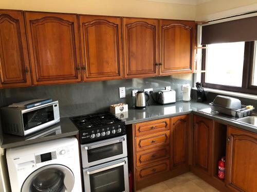 a kitchen with wooden cabinets and a stove top oven at 10 Redcliffe in Stornoway