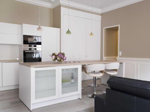 una cocina con armarios blancos y una barra con taburetes en Sasha bel appartement renove centre ville Beaune, en Beaune