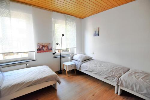 two beds in a room with white walls and wooden ceilings at Central Apartment Bergisch Gladbach in Bergisch Gladbach