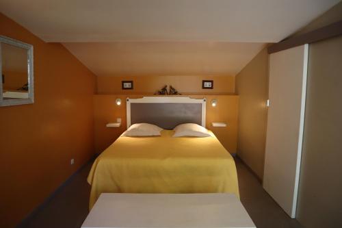 een kleine slaapkamer met een bed met gele lakens bij Domaine des Tilleuls in Marcillac