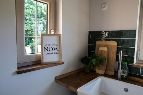 a bathroom with a sink and a window and a sign at Lytte Hytte - Ferienhaus Wingst in Wingst
