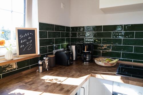 a kitchen with green tiles on the wall at Lytte Hytte - Ferienhaus Wingst in Wingst