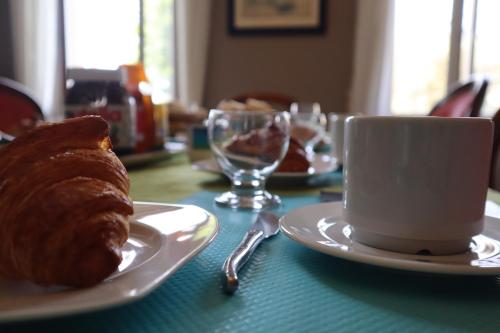 una mesa con una taza de café y un cruasán en Domaine des Tilleuls, en Marcillac