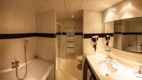 een badkamer met een douche, een wastafel en een bad bij Airport Hotel Basel - Convenient & Friendly in Bazel