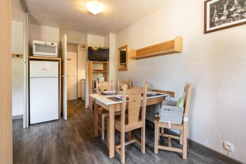 een keuken met een tafel en stoelen en een koelkast bij Neige et Soleil in Montchavin
