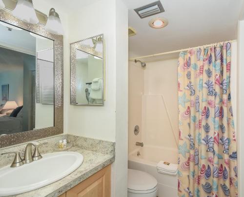 a bathroom with a sink and a toilet and a mirror at Ocean Trillium Suites in New Smyrna Beach