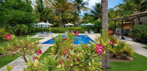 um resort com piscina, palmeiras e flores em Pousada Villages Boutique Hotel - 150m da Praia da Laje em Pôrto de Pedras