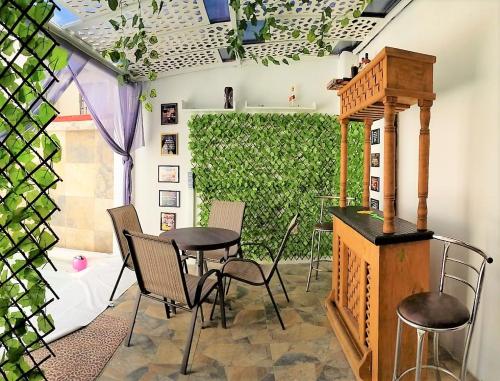 een patio met een tafel en stoelen en een groene heg bij Casa con alberca climatizada privada para 8 personas in Emiliano Zapata