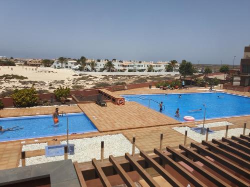 a large swimming pool with people in it next to a beach at Marfolin 11 Beach Front apartment with sea views from every room in Cotillo