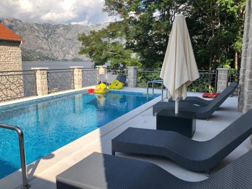 una piscina con sombrilla y sillas junto a una piscina en Zeta Residence en Donji Stoliv