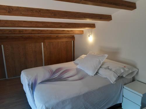 Schlafzimmer mit einem weißen Bett mit einem Kopfteil aus Holz in der Unterkunft La Rosa de los Vientos in Casas del Abad
