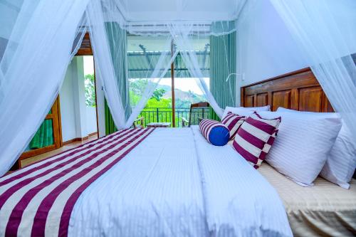 a bedroom with a large bed with striped pillows at Third Eye Ella in Ella