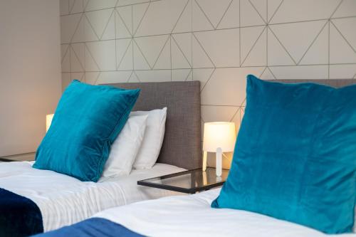 two beds with blue pillows in a room at Iona Residence - Donnini Apartments in Ayr