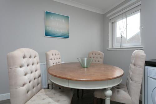 a dining room with a wooden table and white chairs at Iona Residence - Donnini Apartments in Ayr