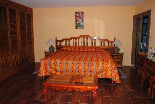a bedroom with a bed with a orange comforter at Hotel Boutique Posada la Casona de Cortés in Tlaxcala de Xicohténcatl
