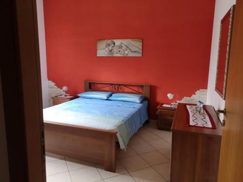 a bedroom with a bed and a red wall at Hawaii Siciliane in Castelluzzo