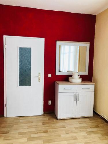a room with red walls and a white door and a mirror at Ferienwohnung Sabine in Schmalkalden