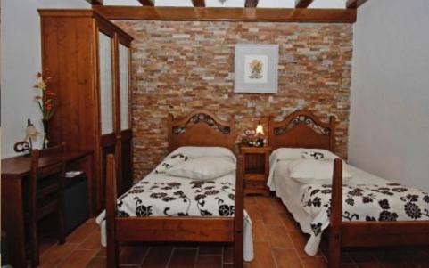a bedroom with two beds and a brick wall at Hotel La Parra in Aliaga