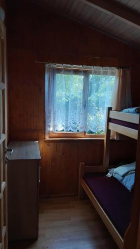 a bedroom with a bunk bed and a window at 2 Bursztyny in Rusinowo