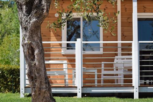 a wooden house with a white railing next to a tree at Campeggio Europa Silvella in San Felice del Benaco