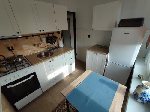 a small kitchen with white cabinets and a white refrigerator at Mieszkanie z dobrą energią in Giżycko